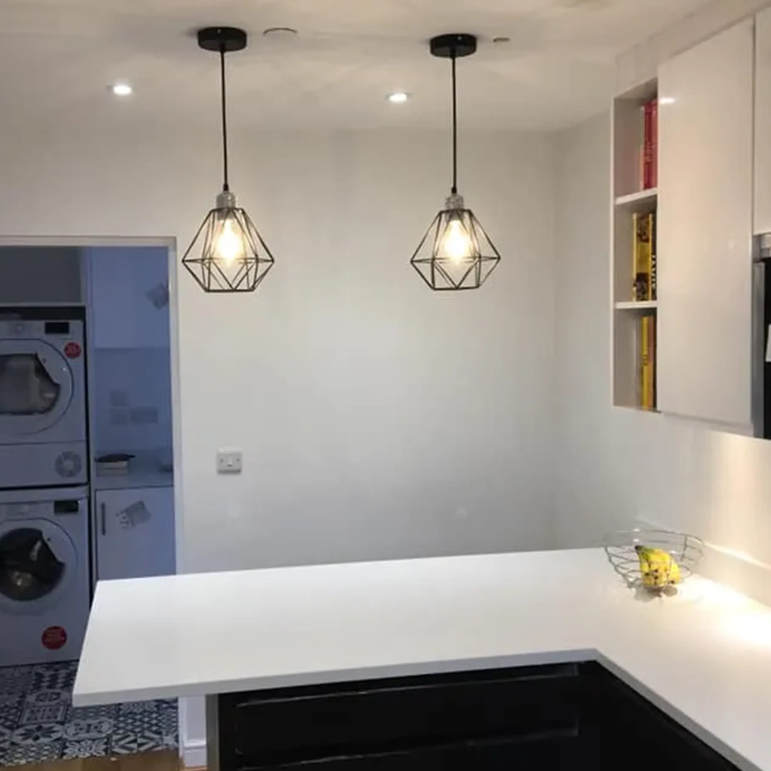 A kitchen with a white counter top next to a washer and dryer.