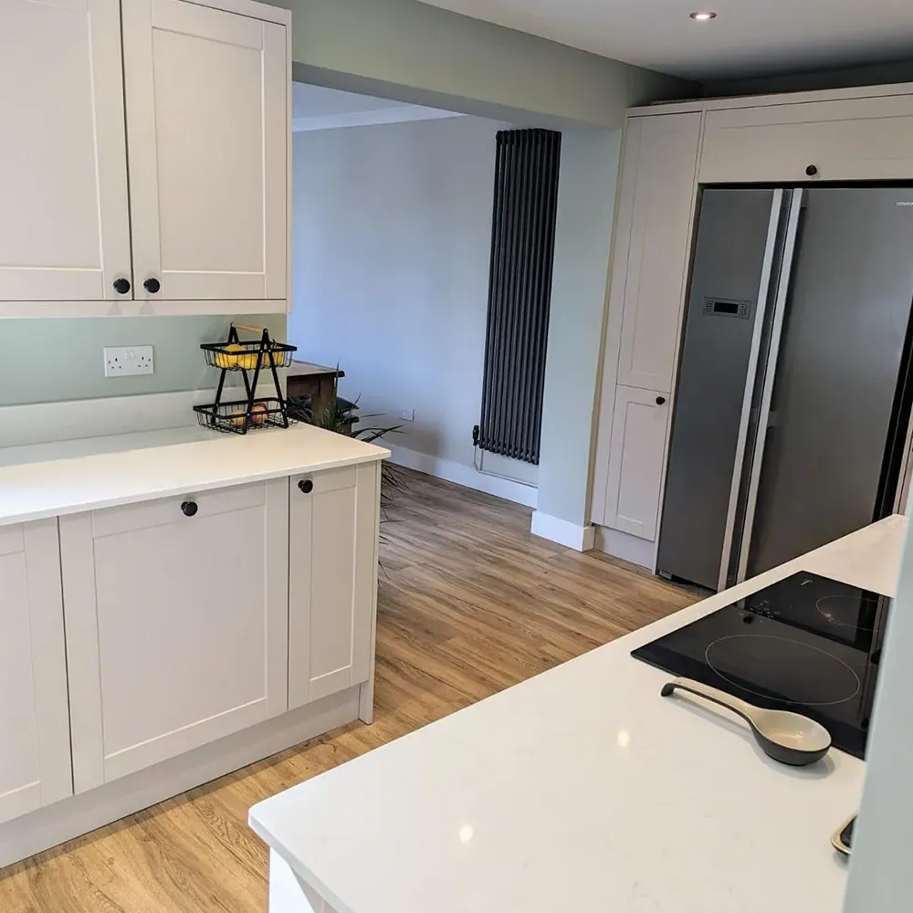 A kitchen with white cabinets and a refrigerator.