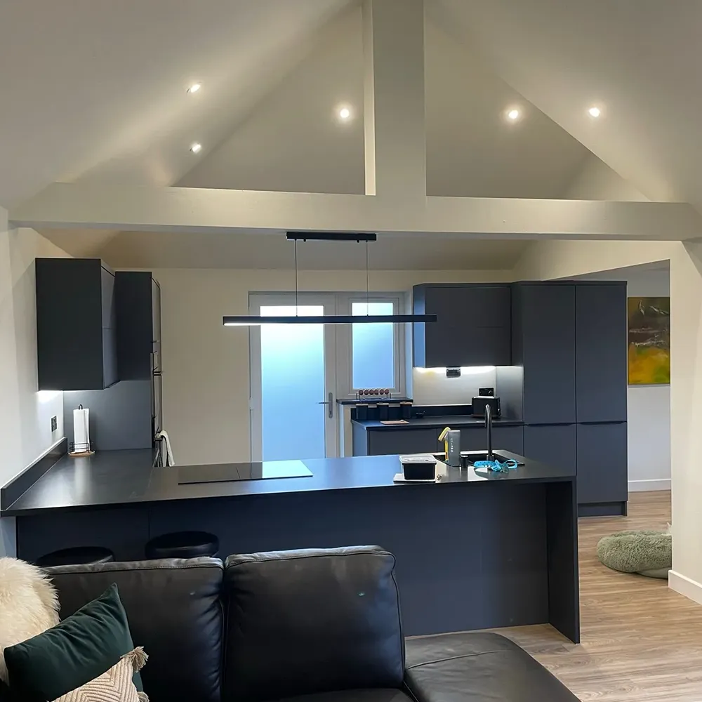 a modern kitchen and living room with a black couch