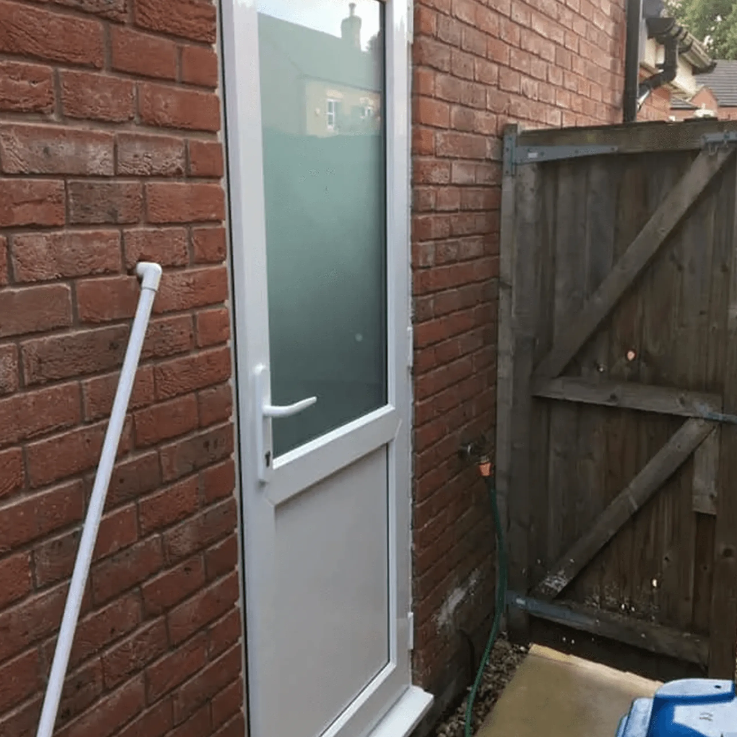 A white door is open on a brick building.