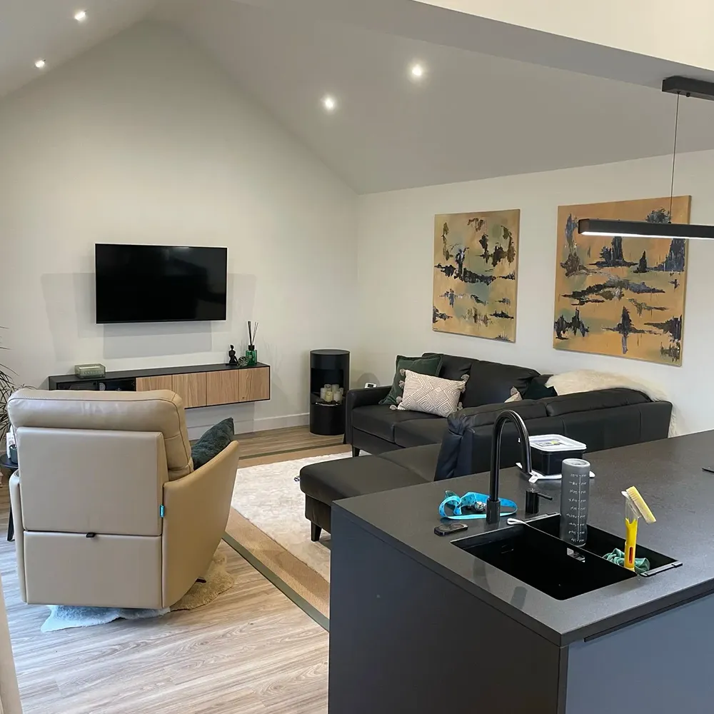 A kitchen and living room with a television on the wall.