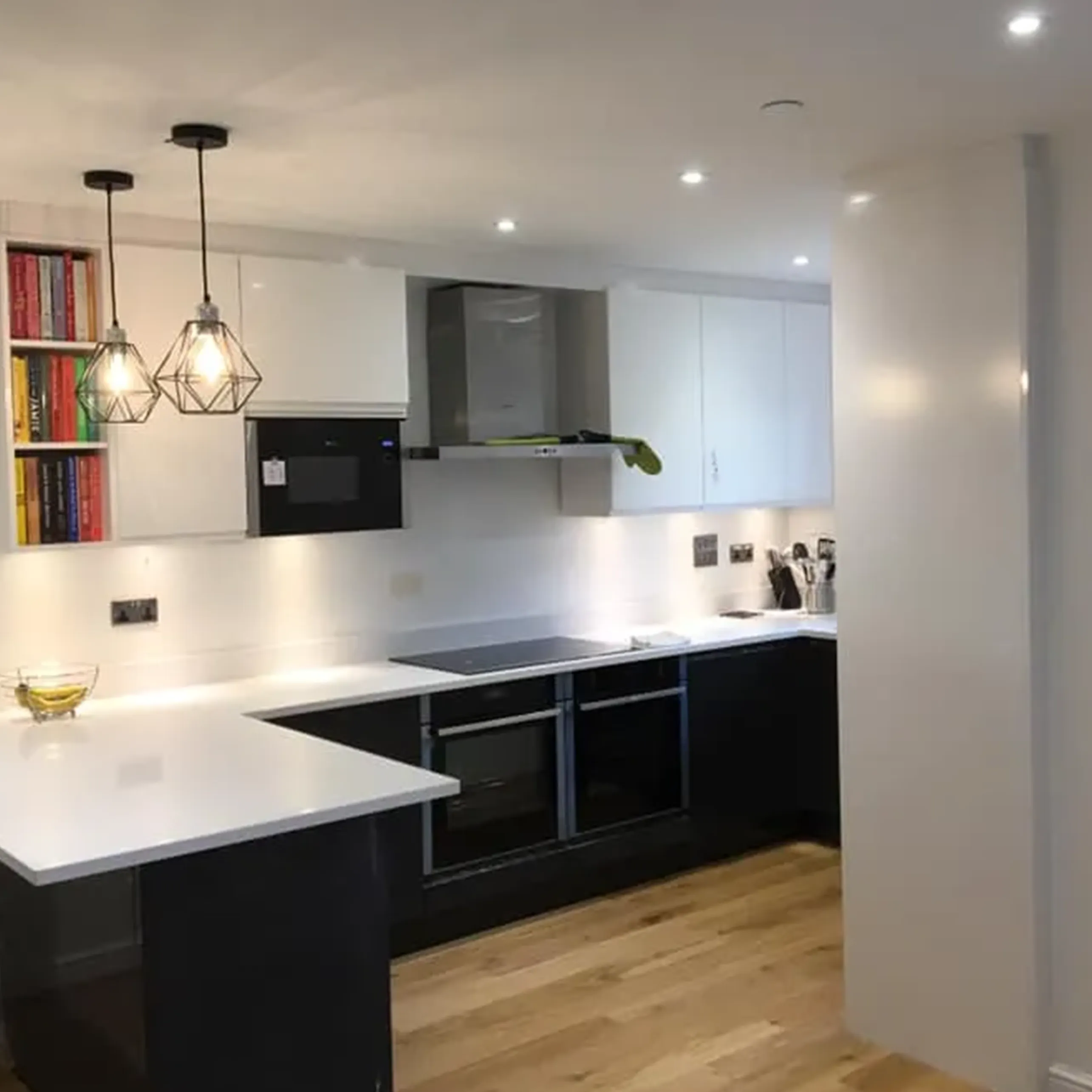 A kitchen with a white counter top and black cabinets.
