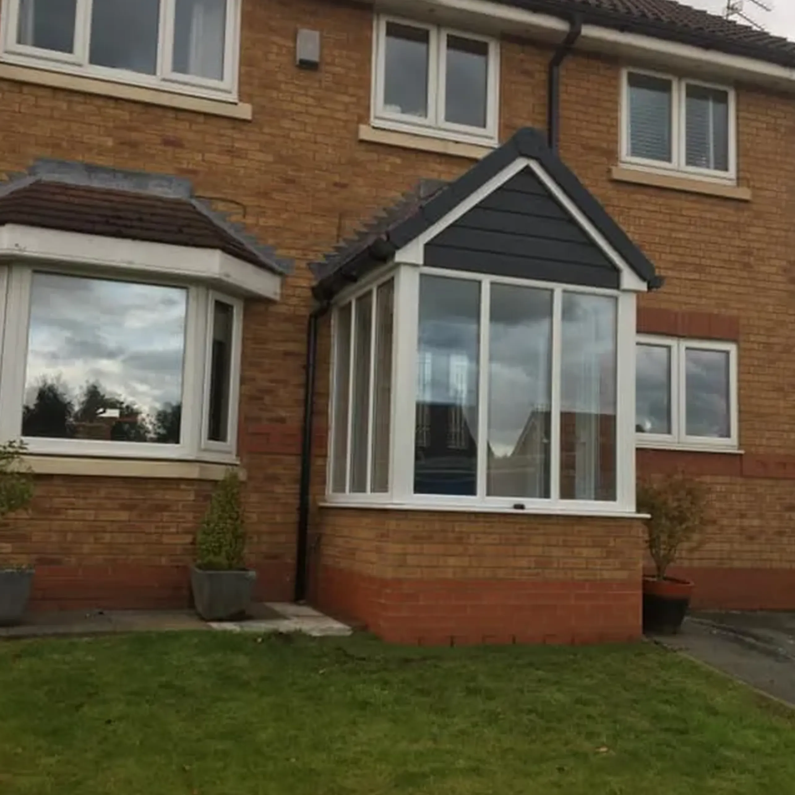 A two story brick house with white windows.