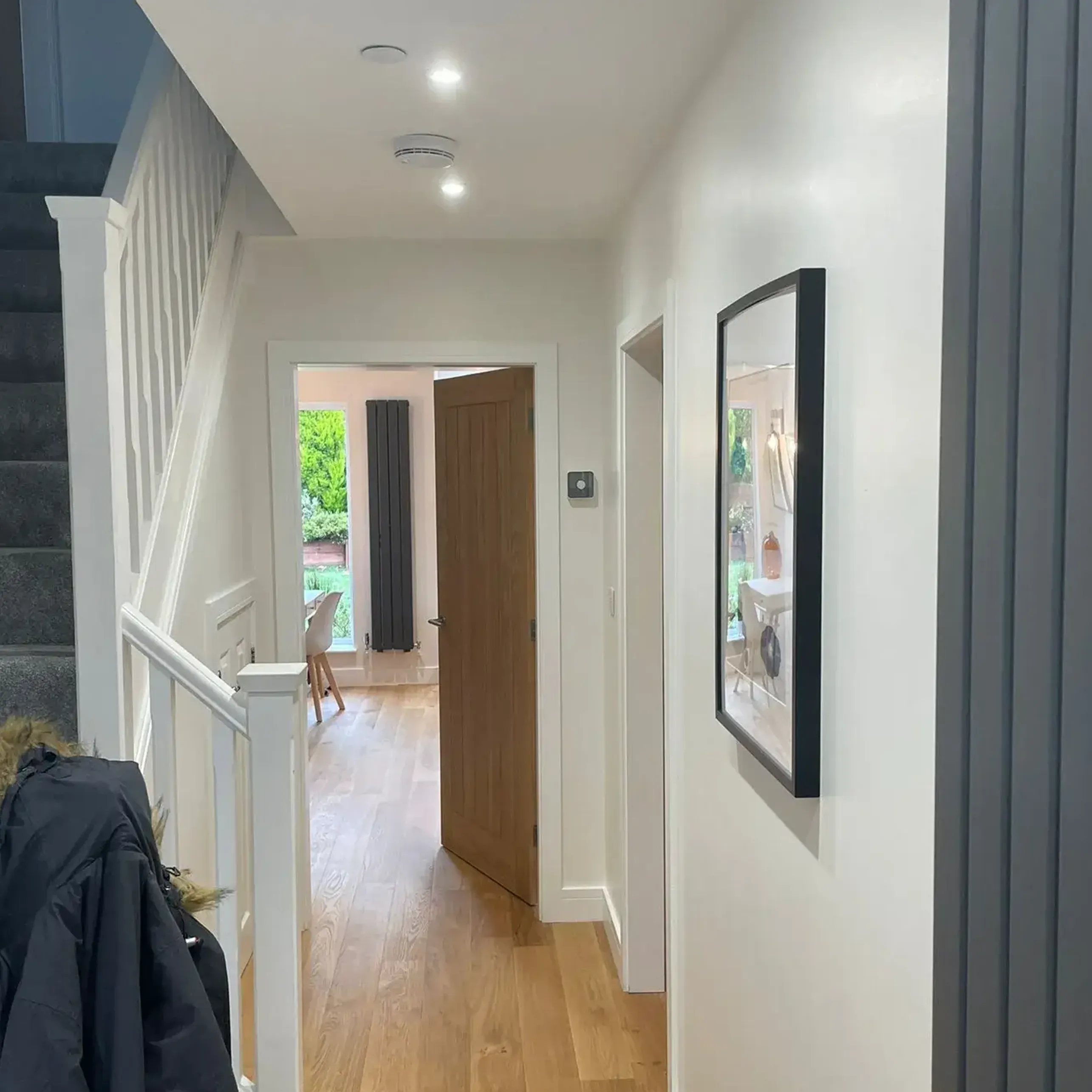 A hallway with a wooden floor and white walls.