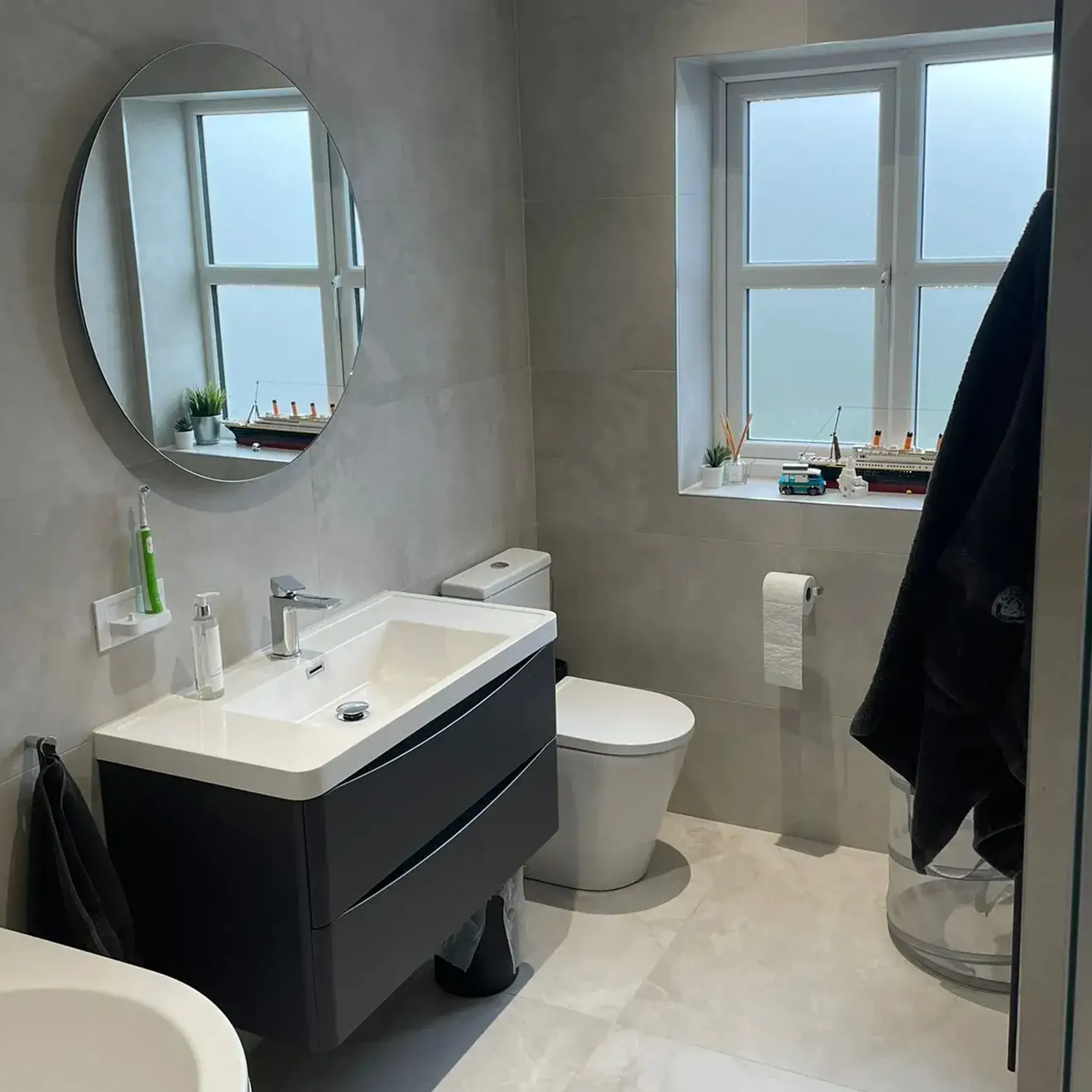 A bathroom with a toilet, sink, and mirror.