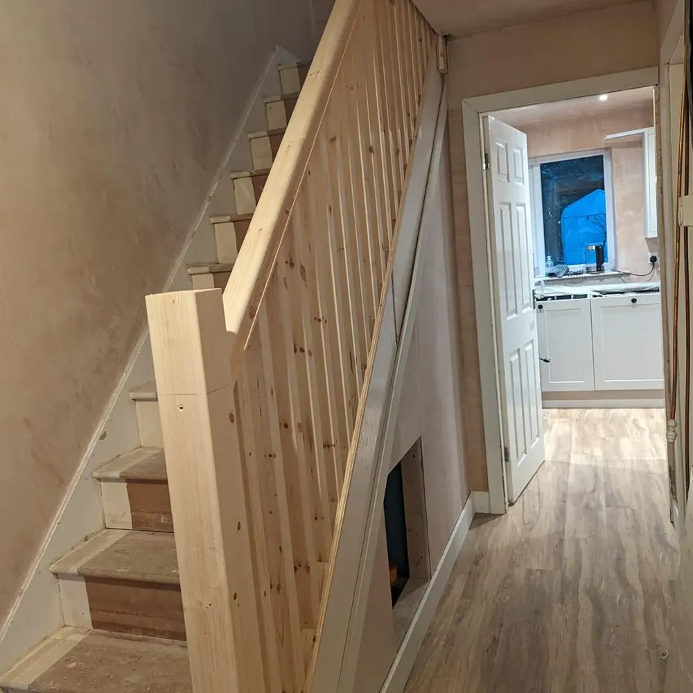 A wooden staircase leading up to a kitchen.